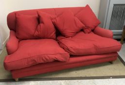 A modern red felt effect upholstered sofa on turned front legs in the manner of Howard of London,