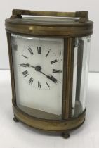 A circa 1900 French brass cased mantel clock of oval form, the enamelled dial with Roman numerals,