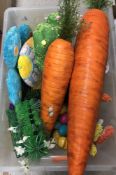 A box of Easter themed decorations to include over sized carrots, hanging Easter egg,