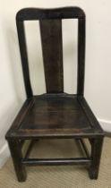 An early 18th Century Welsh Provincial oak dining chair with plain slat back over a panel seat,