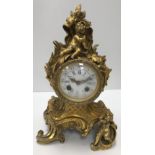 A 19th Century French gilt brass cased mantel clock in the Rococo taste with putti decoration