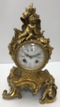 A 19th Century French gilt brass cased mantel clock in the Rococo taste with putti decoration