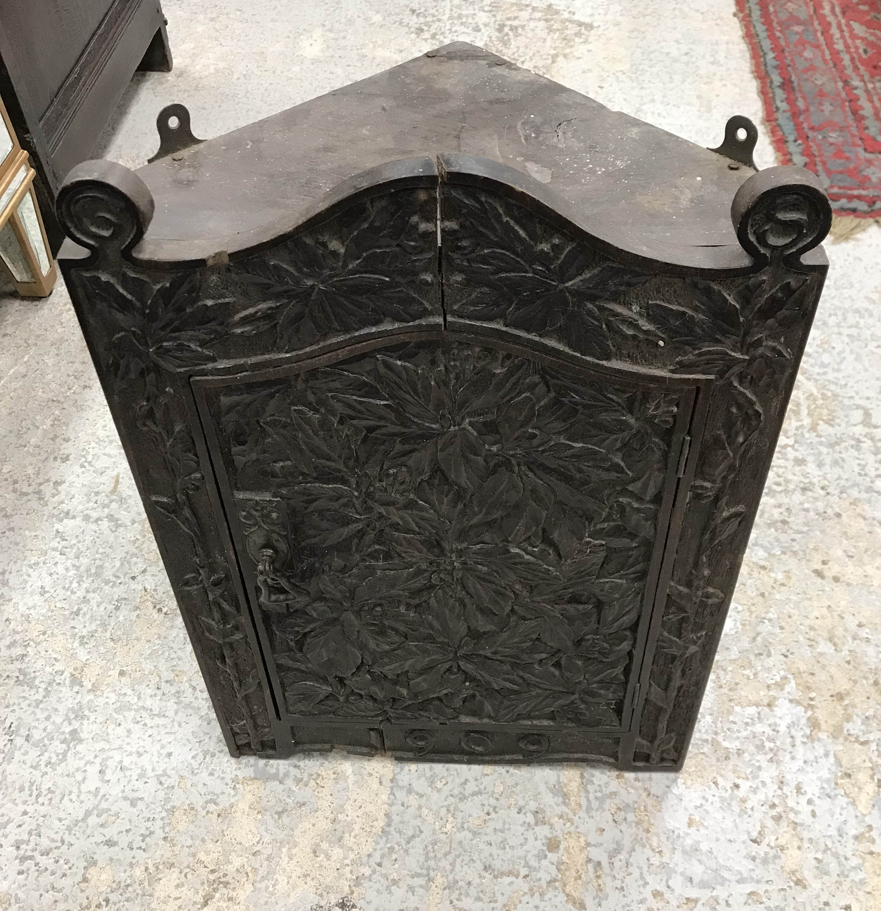 An Edwardian carved oak hanging corner cupboard in the Arts & Crafts style,
