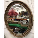 A large Victorian oval carved giltwood framed wall mirror with ribbon acanthus and beaded