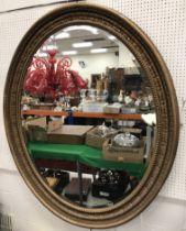 A large Victorian oval carved giltwood framed wall mirror with ribbon acanthus and beaded