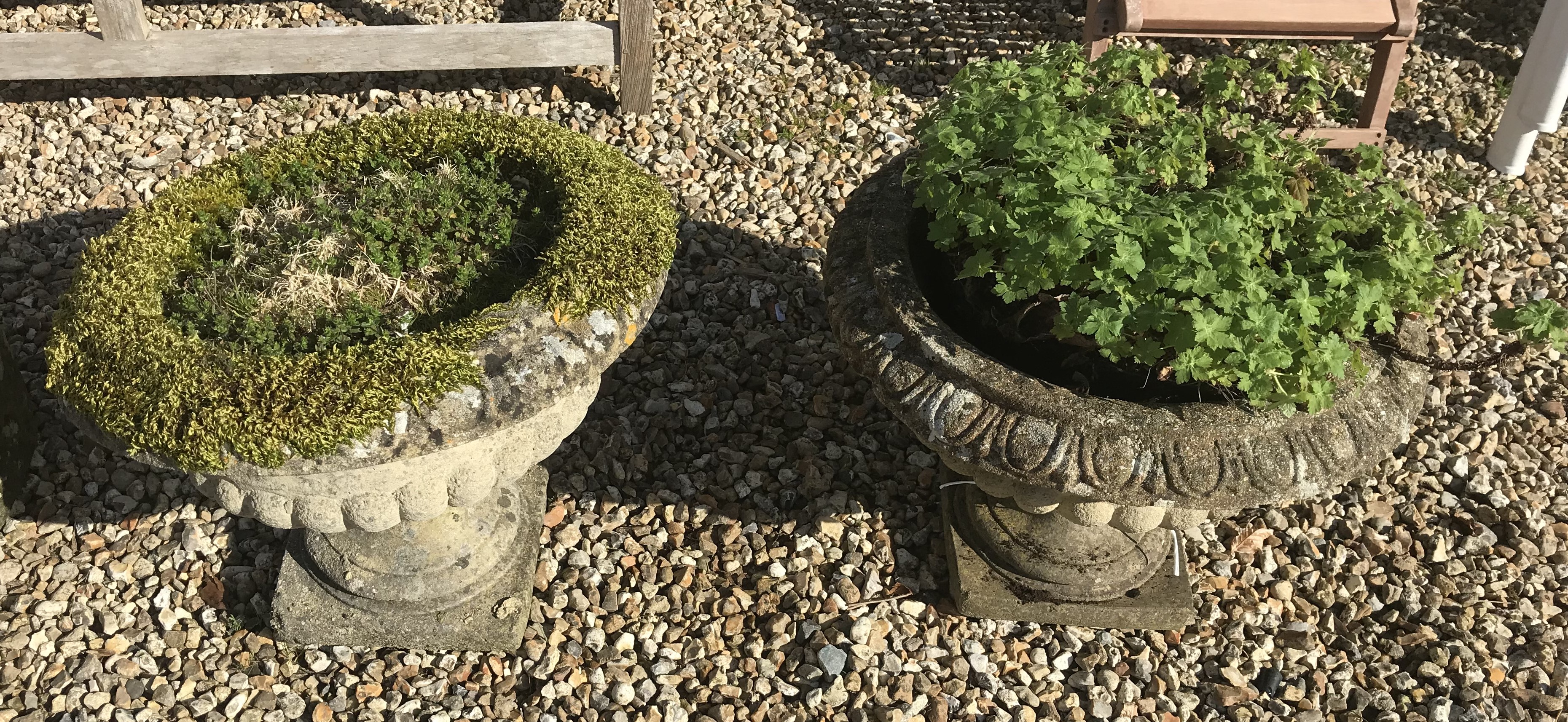 A pair of reconstituted stone garden urns on bases