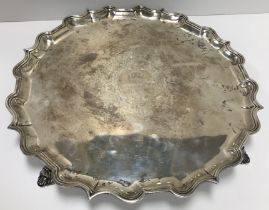 A George II silver salver with pie crust edge raised on four scrolling feet bearing inscription