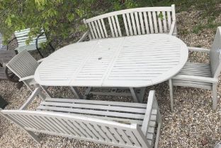 A large painted teak garden table 241 x 110 x 72 cm high with two benches and two chairs