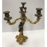 WITHDRAWN A gilt brass Rococo style candle holder as a satyr holding aloft three acanthus