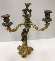 WITHDRAWN A gilt brass Rococo style candle holder as a satyr holding aloft three acanthus