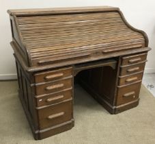 A circa 1900 American tambour or roll top desk, with basic fitted interior, over a central drawer,