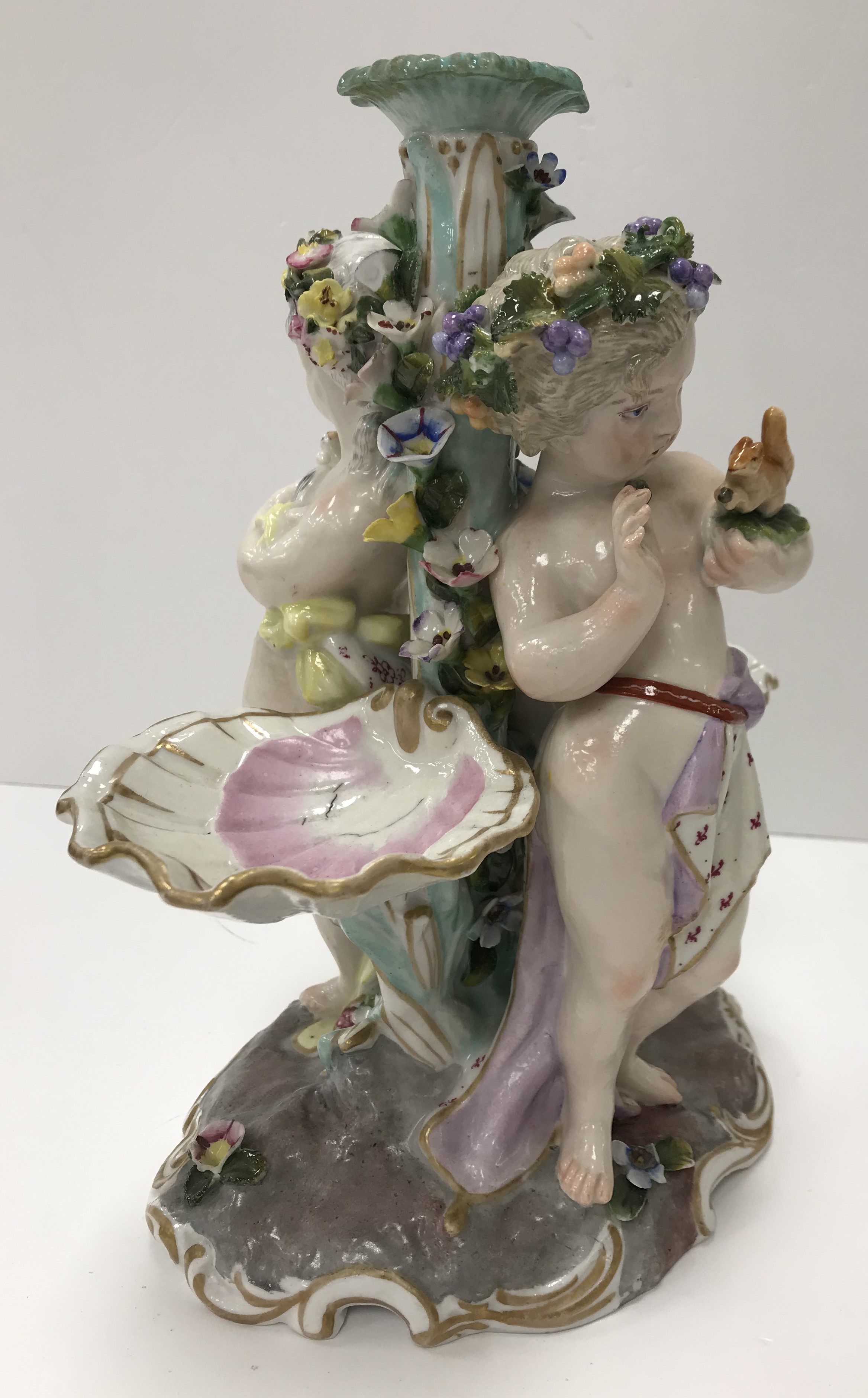 A Meissen style table centre base of two putti, one with squirrrel,