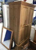 A modern pine wardrobe with two twin panelled doors enclosing hanging space over a single drawer,