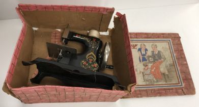 A vintage German painted tin child's sewing machine (boxed) 23 cm long x 11.