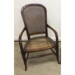 A late Victorian mahogany framed and caned open arm elbow chair on turned and ringed legs united by