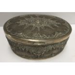 A Continental white metal hinge lidded box of oval form with embossed stylised floral decoration