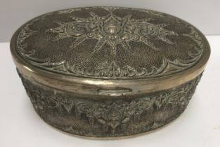 A Continental white metal hinge lidded box of oval form with embossed stylised floral decoration