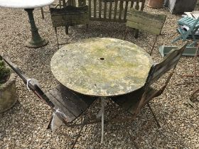 A weathered wrought iron circular garden table and four slatted wooden seated wrought iron framed