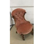 A Victorian carved walnut framed salmon pink buttoned upholstered salon chair on cabriole legs to