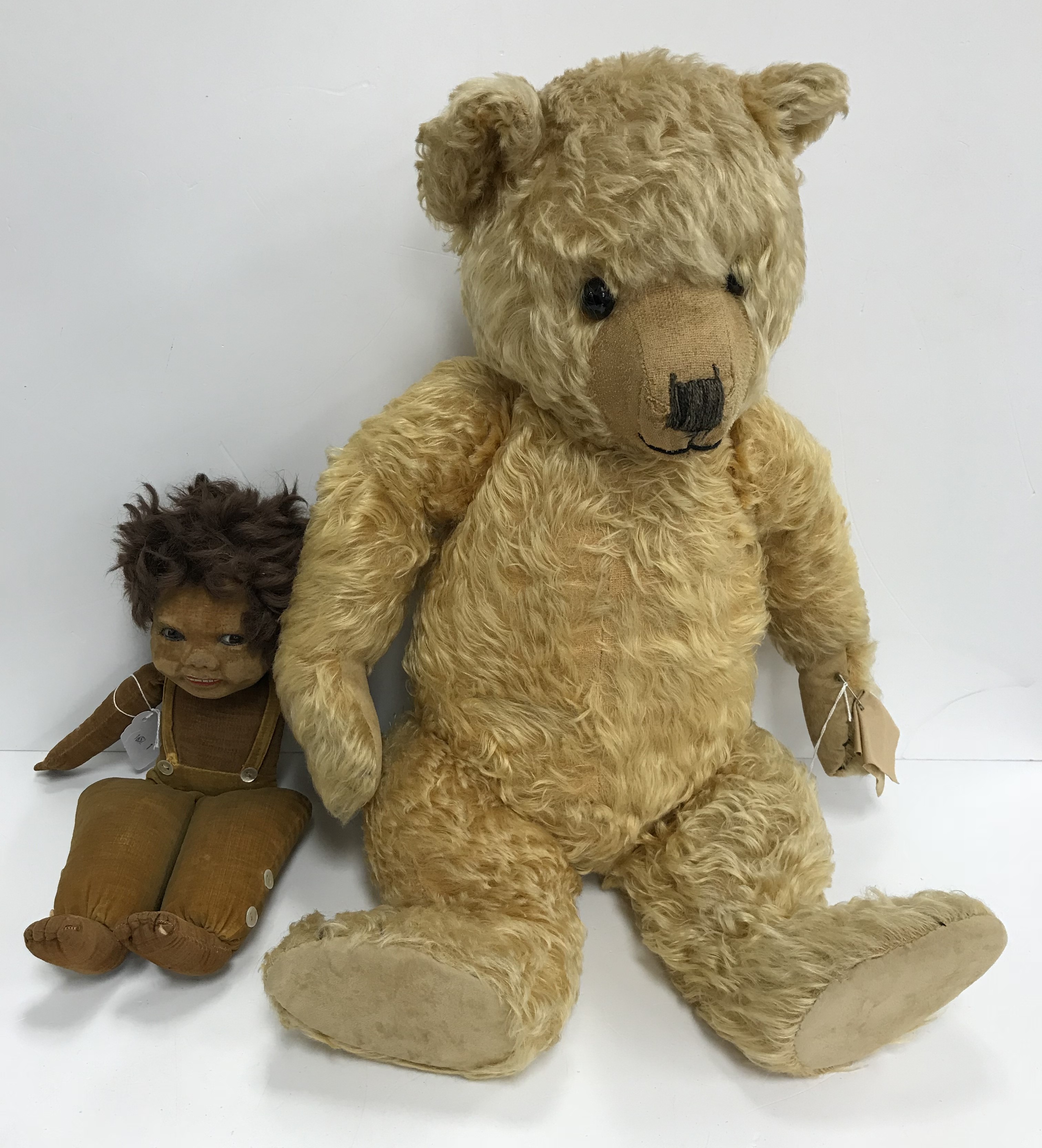 An early to mid 20th Century gold plush teddy bear with stitched nose and mouth and glass eyes,