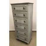 A painted pine slim chest of six drawers with ring handles on turned feet,