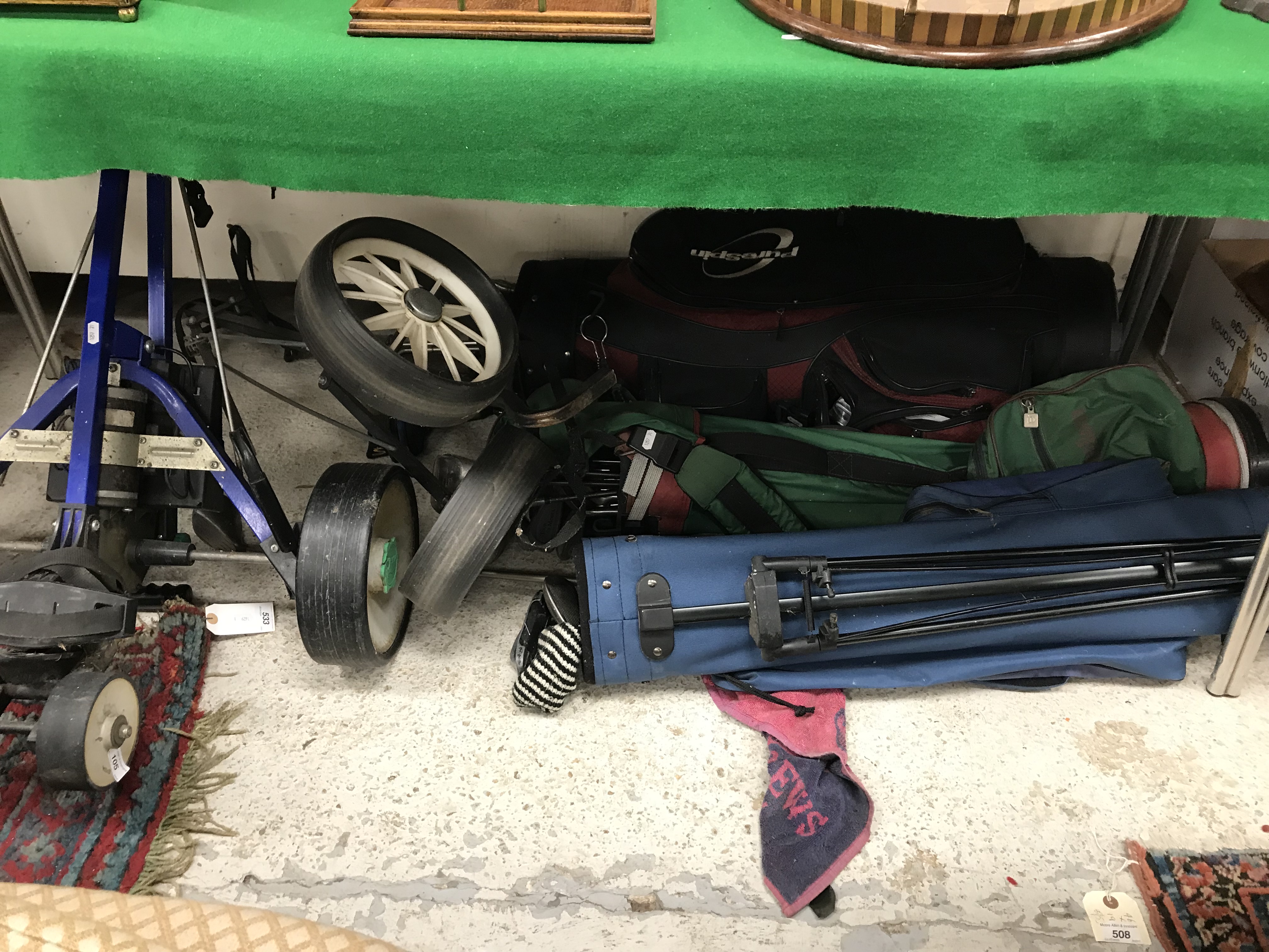 Three golf bags and contents of various golfing irons and woods and two trolleys