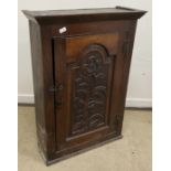 A 19th Century oak cupboard, the canted cornice over an arched panelled door, carved with a flower,