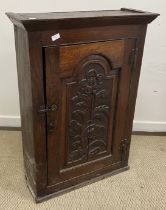 A 19th Century oak cupboard, the canted cornice over an arched panelled door, carved with a flower,