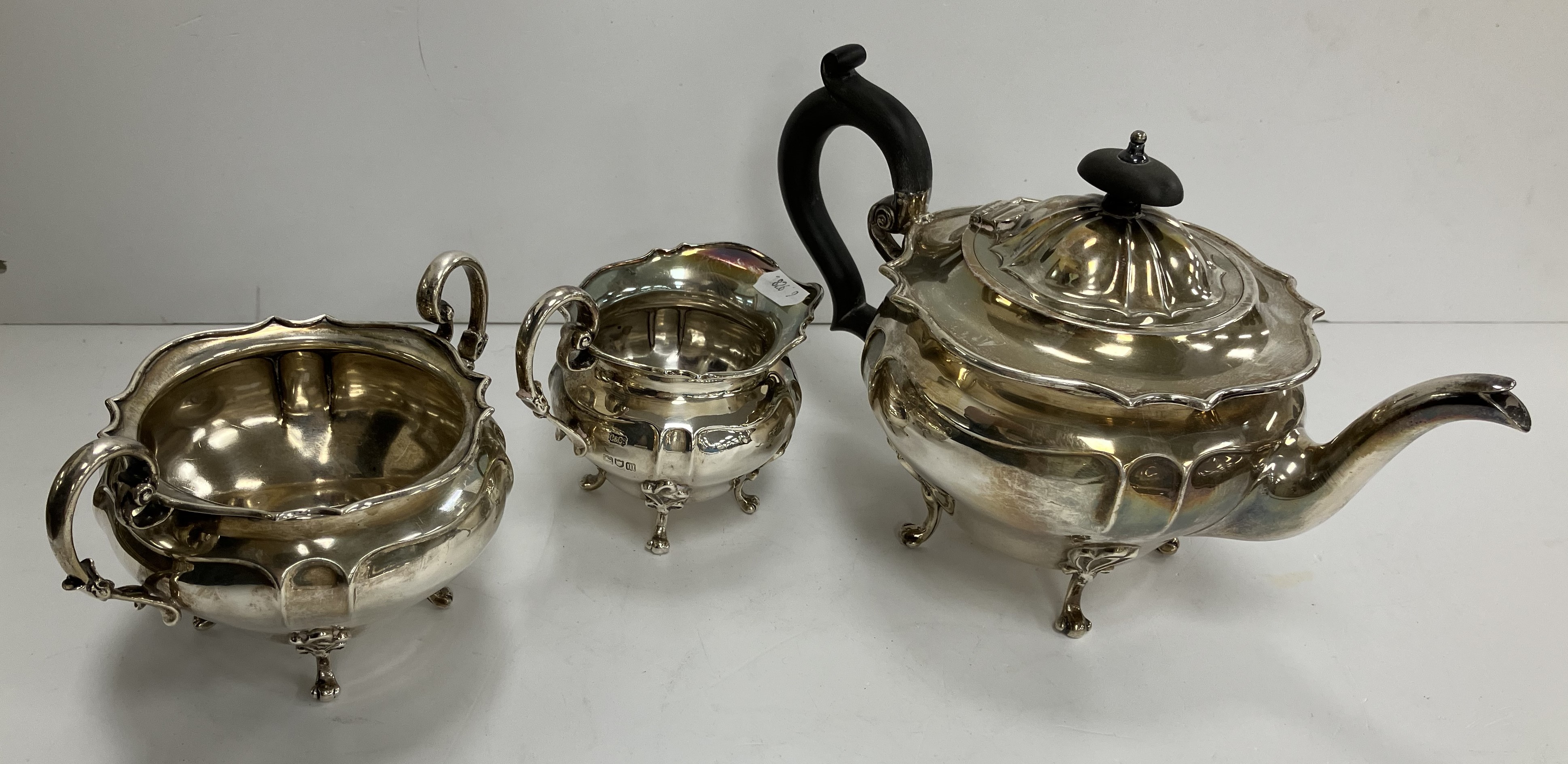 An Edwardian silver three piece tea set of squash form raised on four scroll feet comprising tea