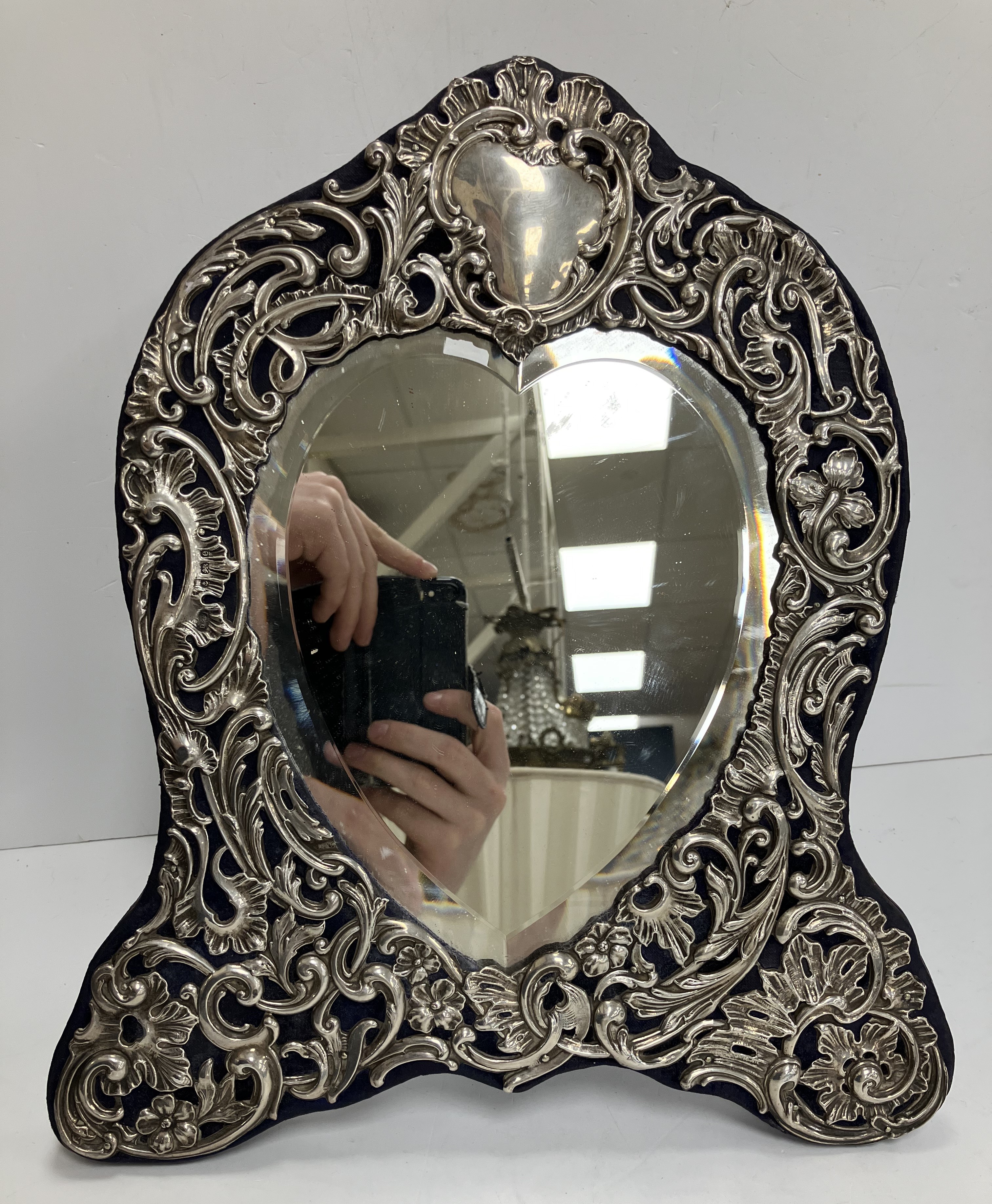 An Edwardian pierced and embossed silver embellished easel mirror with central bevel edged love