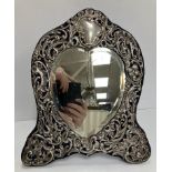 An Edwardian pierced and embossed silver embellished easel mirror with central bevel edged love