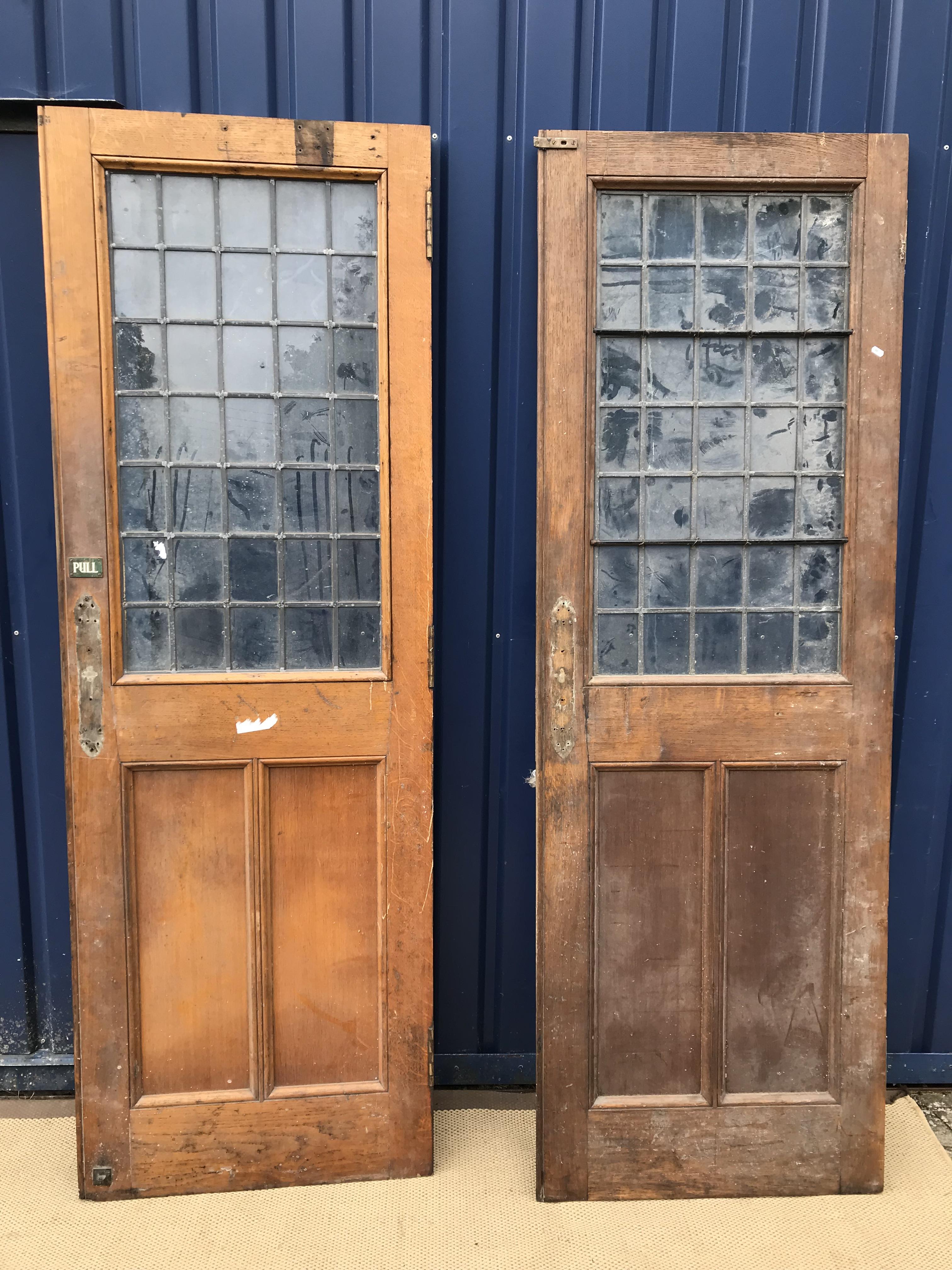A pair of oak interior doors with leaded glazed panels over twin oak panels,