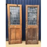 A pair of oak interior doors with leaded glazed panels over twin oak panels,