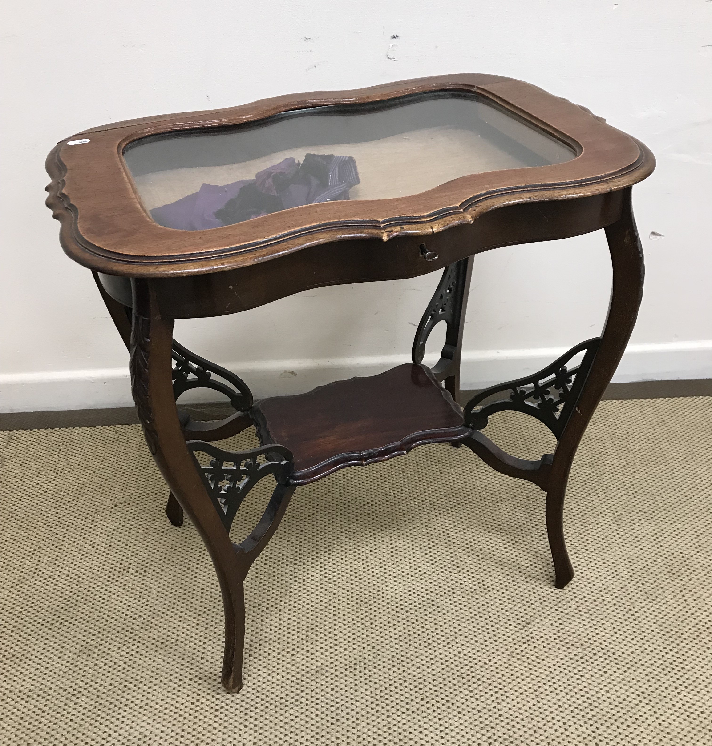 An Edwardian mahogany bijouterie table on cabriole legs united by an under tier,