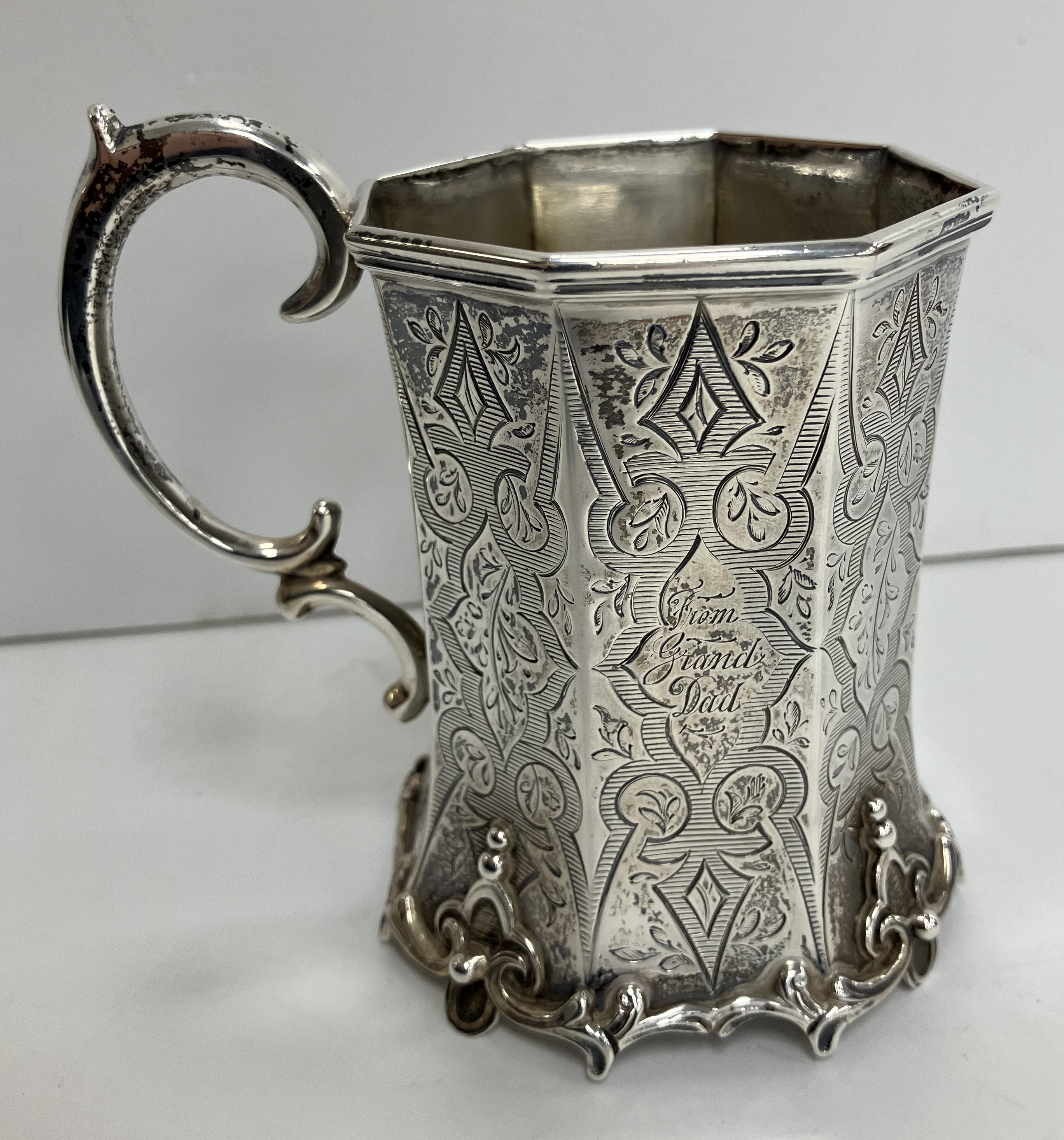 A Victorian silver waisted octagonal Christening mug with Gothic style engraved decoration raised