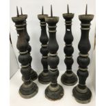 A set of black painted and gilded treenware pricket candlestics with iron spikes raised on circular