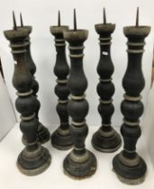 A set of black painted and gilded treenware pricket candlestics with iron spikes raised on circular