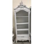 A modern white painted shelf unit in the Louis XV taste with adjustable shelving over a single
