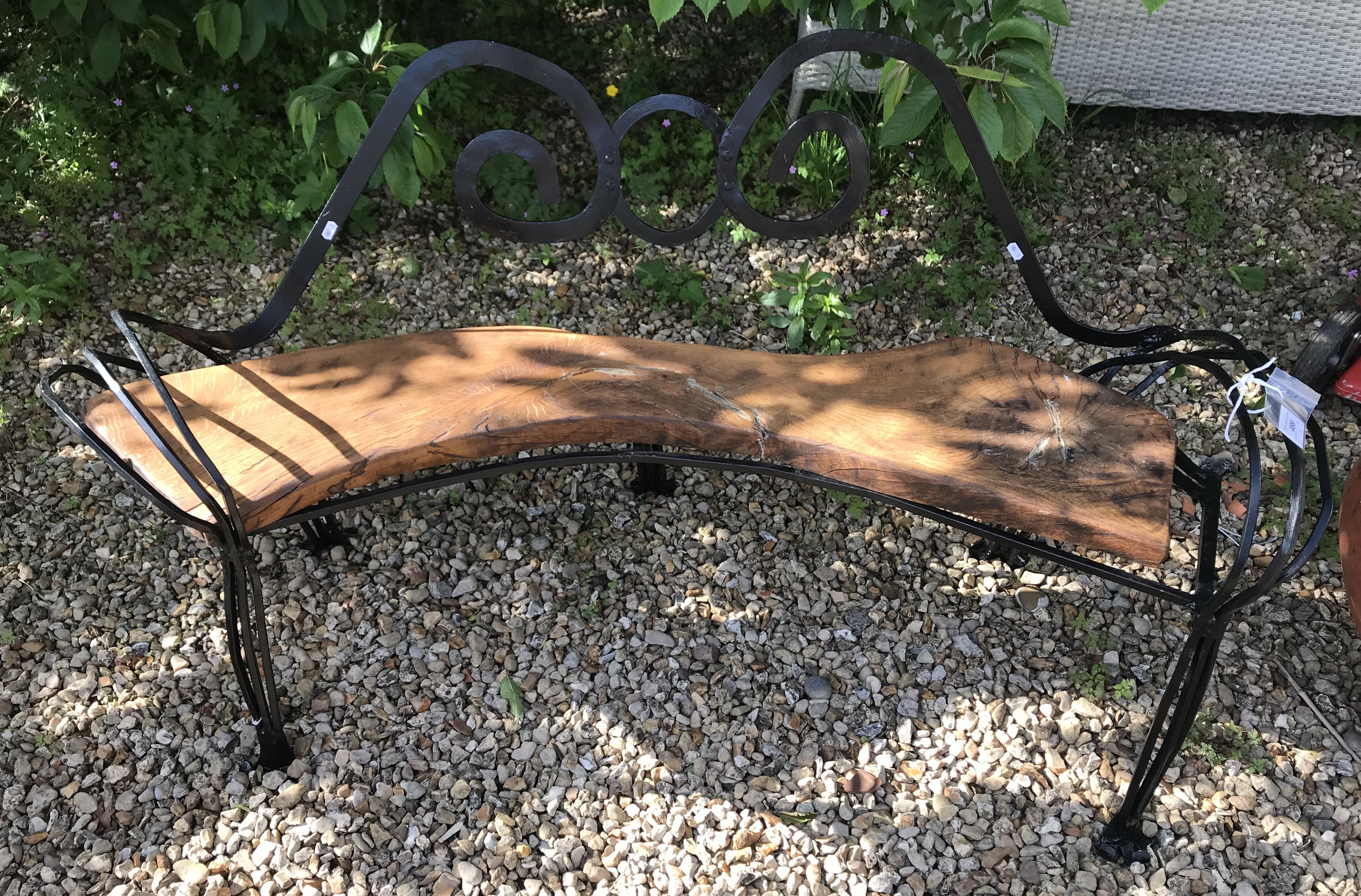 A black painted wrought iron bench with wooden seat,
