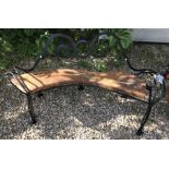 A black painted wrought iron bench with wooden seat,