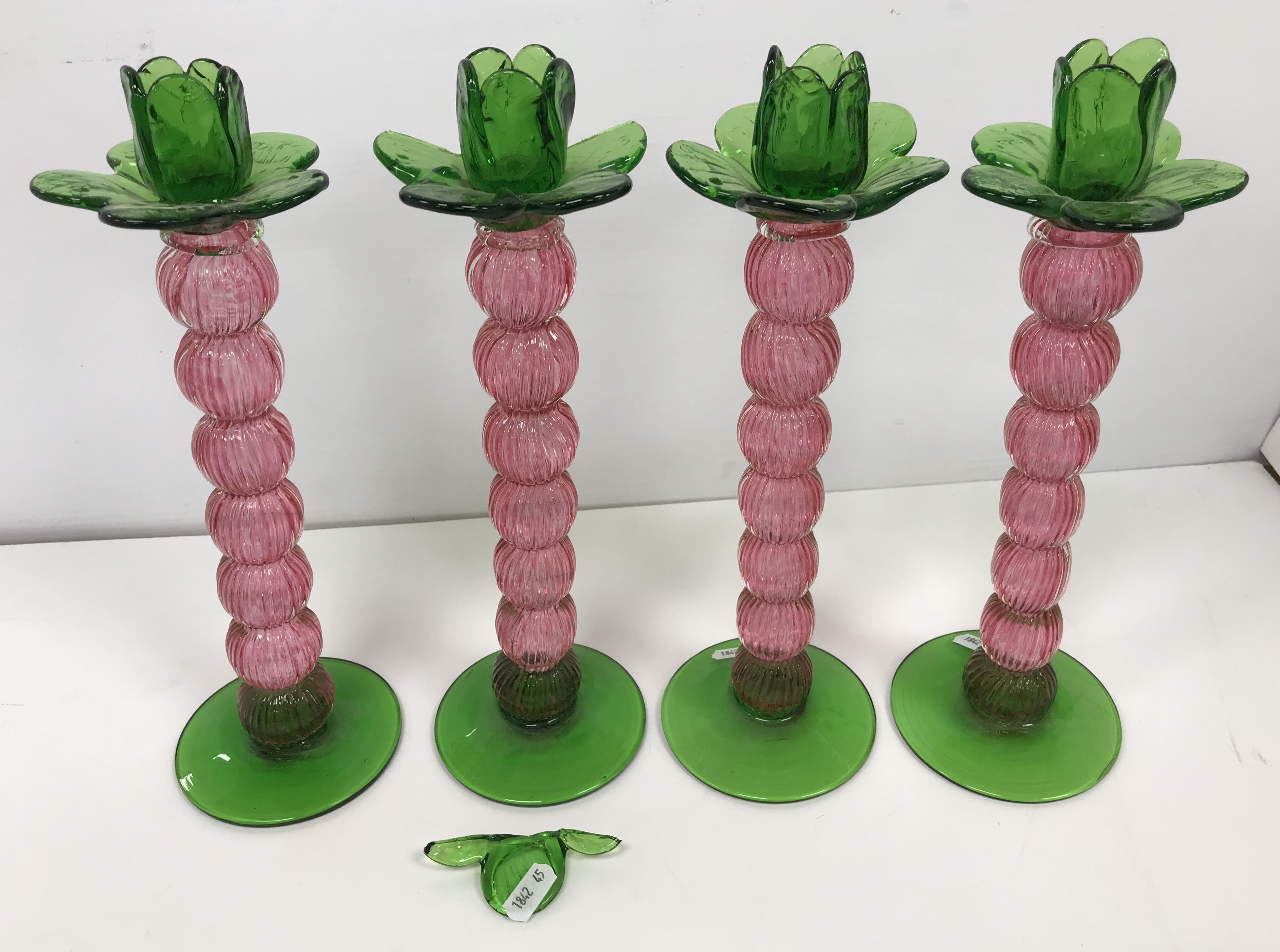 A set of four Continental reeded cranberry glass knop stemmed candlesticks with green glass flower