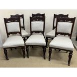 A set of six late Victorian carved mahogany framed dining chairs with upholstered back panels and