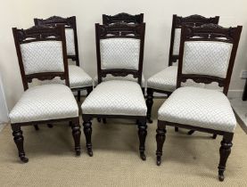 A set of six late Victorian carved mahogany framed dining chairs with upholstered back panels and