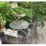 A weathered wrought iron circular garden table and four slatted wooden seated wrought iron framed