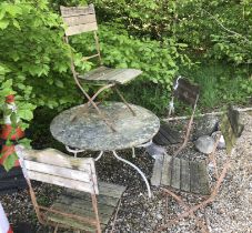 A weathered wrought iron circular garden table and four slatted wooden seated wrought iron framed