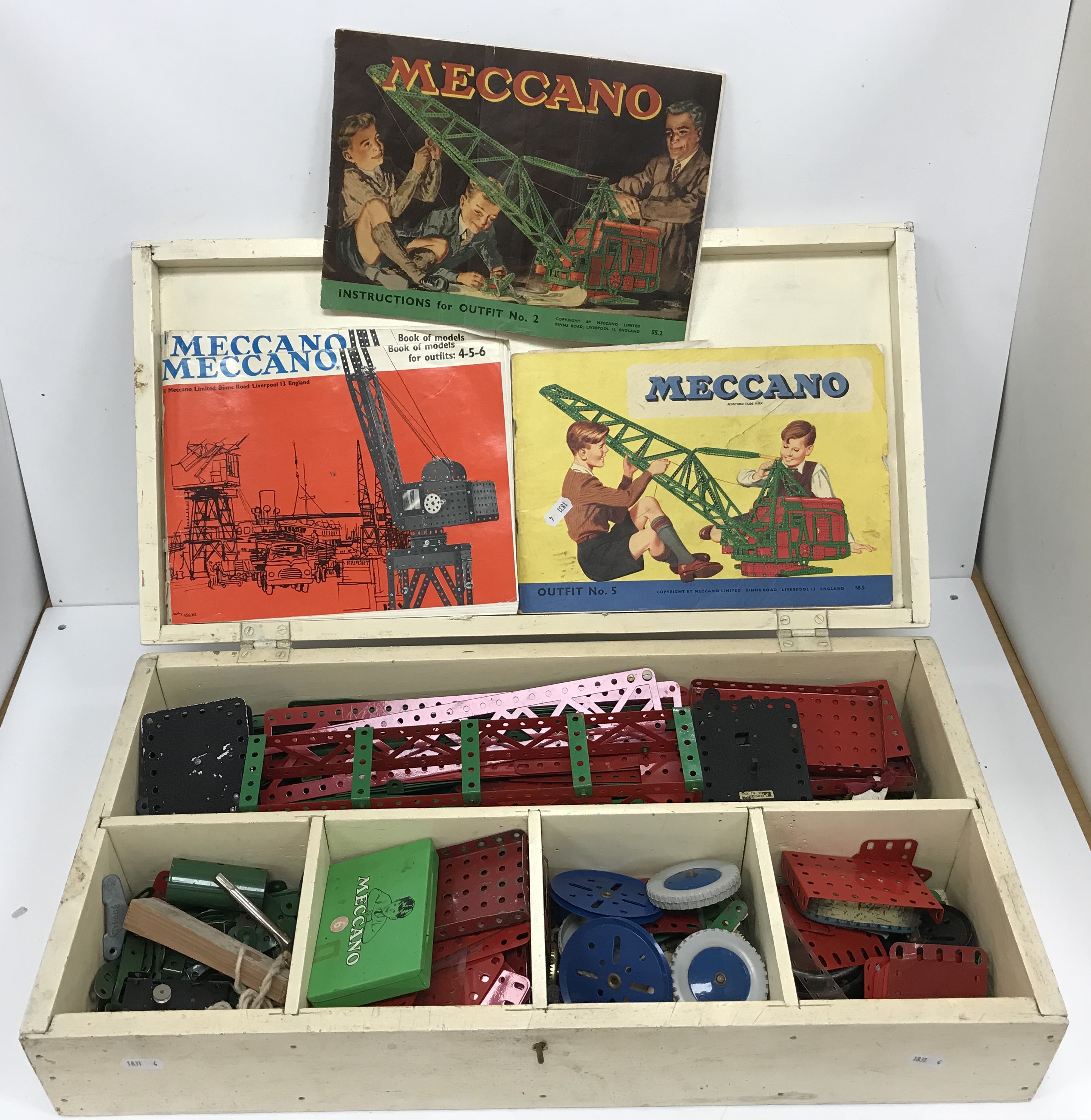 A wooden box containing assorted Meccano together with Meccano instruction booklets comprising