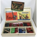 A wooden box containing assorted Meccano together with Meccano instruction booklets comprising