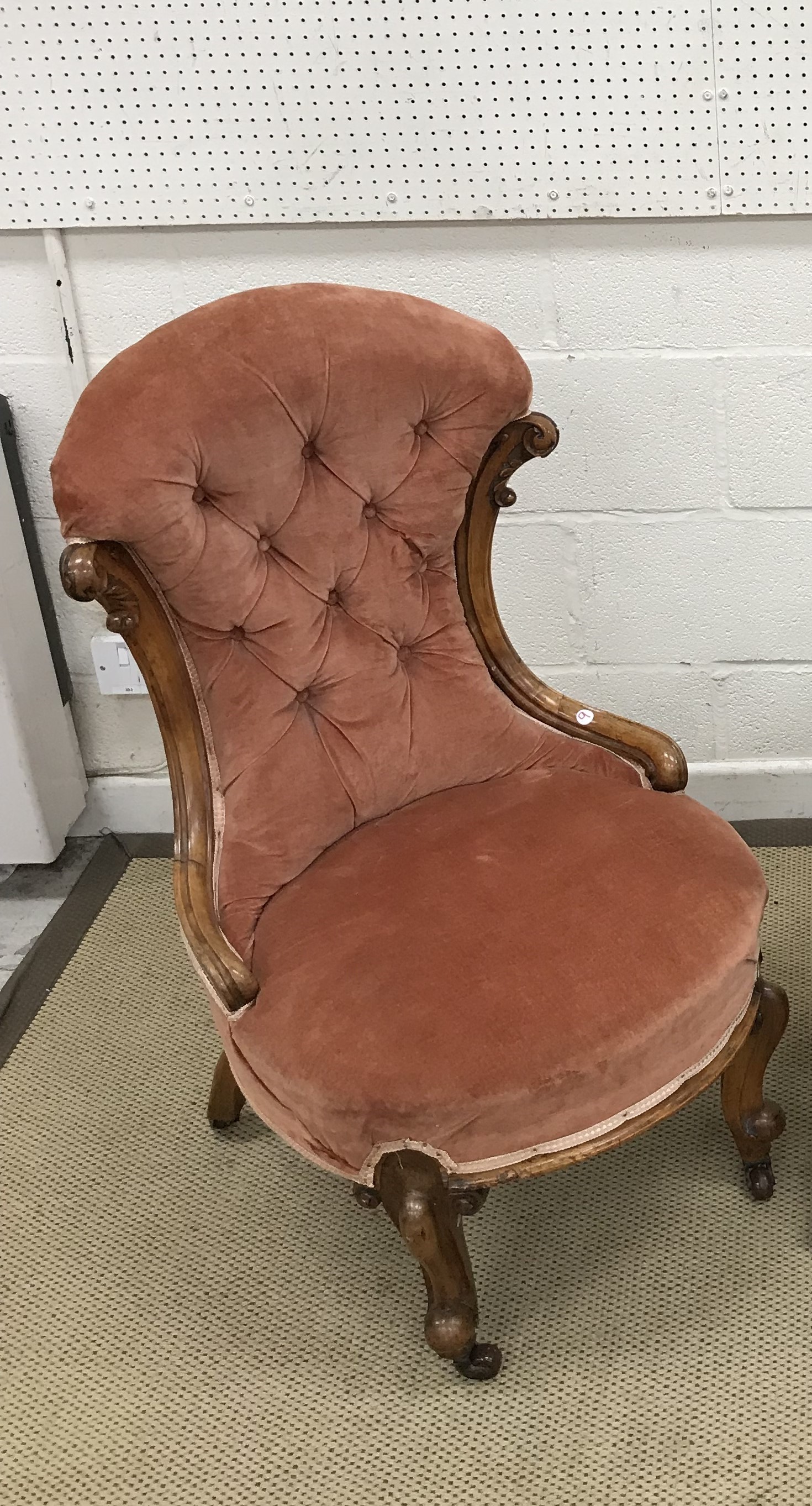 A Victorian carved walnut framed salmon pink buttoned upholstered salon chair on cabriole legs to