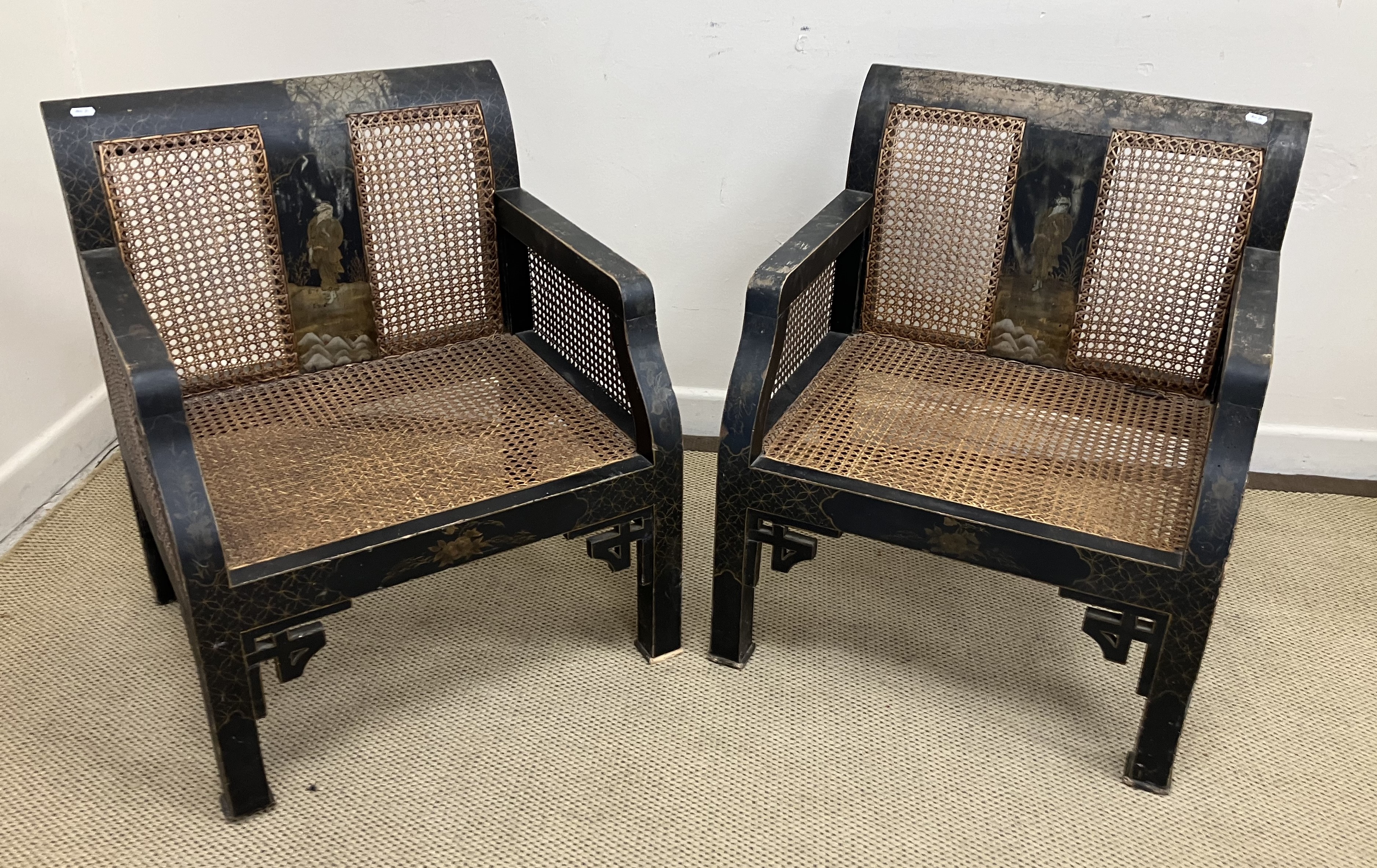 A pair of early 20th Century black lacquered and chinoiserie decorated caned low arm chairs on