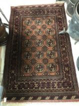 A Bokhara rug, the central panel set with repeating medallions on a rust ground, within a red,